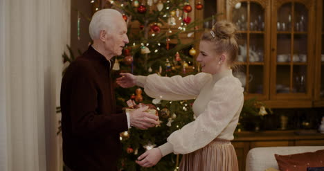 Woman-Giving-Christmas-Present-To-Grandfather-At-Home-5