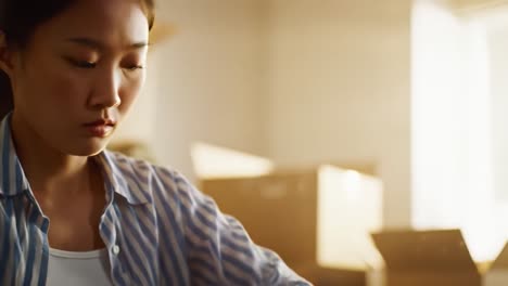 a focused young woman meticulously organizes her workspace in a bright room, demonstrating dedication and attention to detail in her task