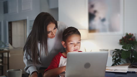 Mujer-Hispana-Ayudando-A-Su-Hijo-Mientras-Hace-Su-Tarea-Con-Una-Computadora-Portátil,-Vista-Lateral,-De-Cerca