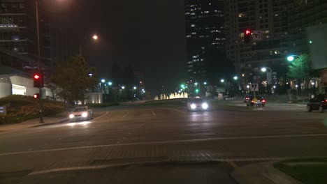a car travels along a street at night in century city los angeles as seen through the rear window 2