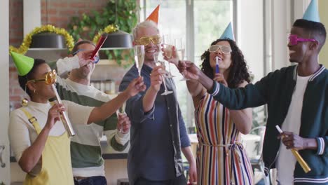 Happy-group-of-diverse-friends-in-party-hats-celebrating-together,-toasting-with-vine