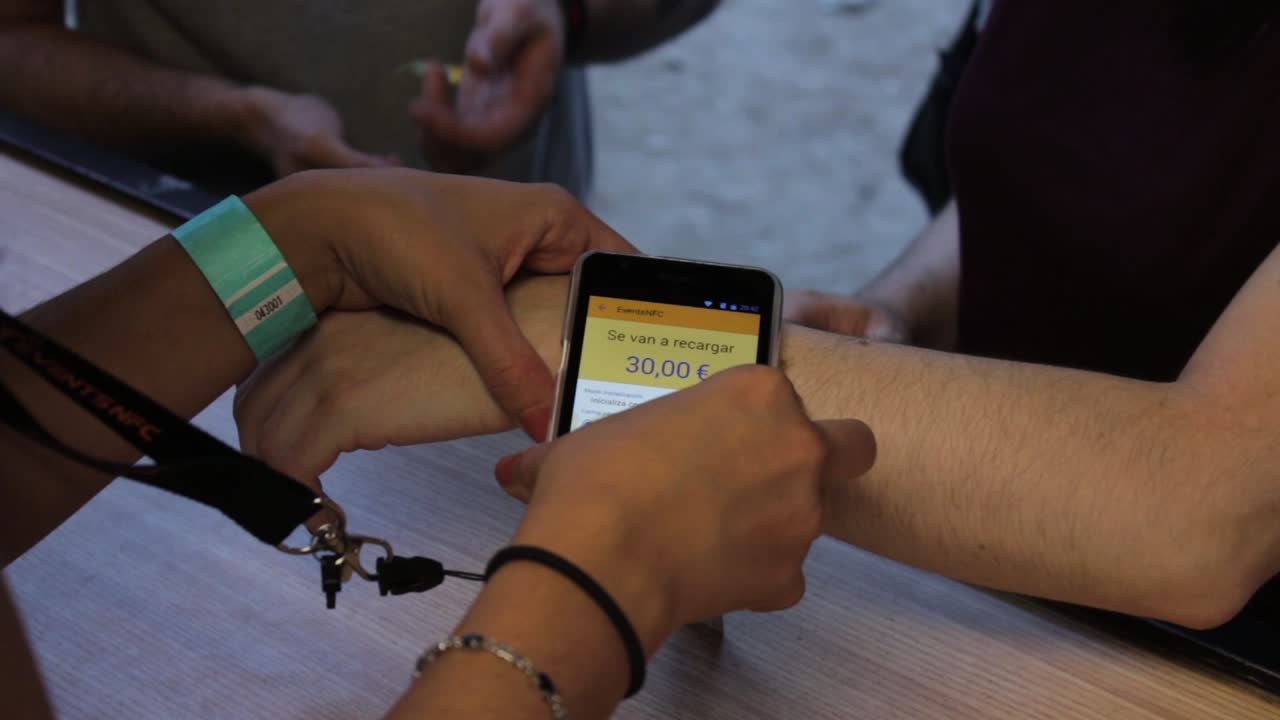 Close shot of a woman making an nfc payment with its wristband on a music festival.