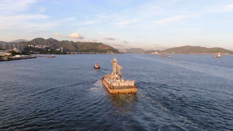 remolcador tirando de una pequeña barcaza en la bahía de hong kong, vista aérea