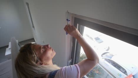 Woman-With-Paint-Brush-Painting-Around-Window-During-DIY-Paint-Job-High-Angle-In-Slow-Motion