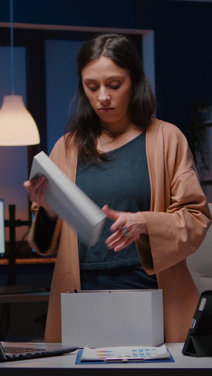 Vertical video Dismissed unhappy businesswoman packing company stuff putting in white box