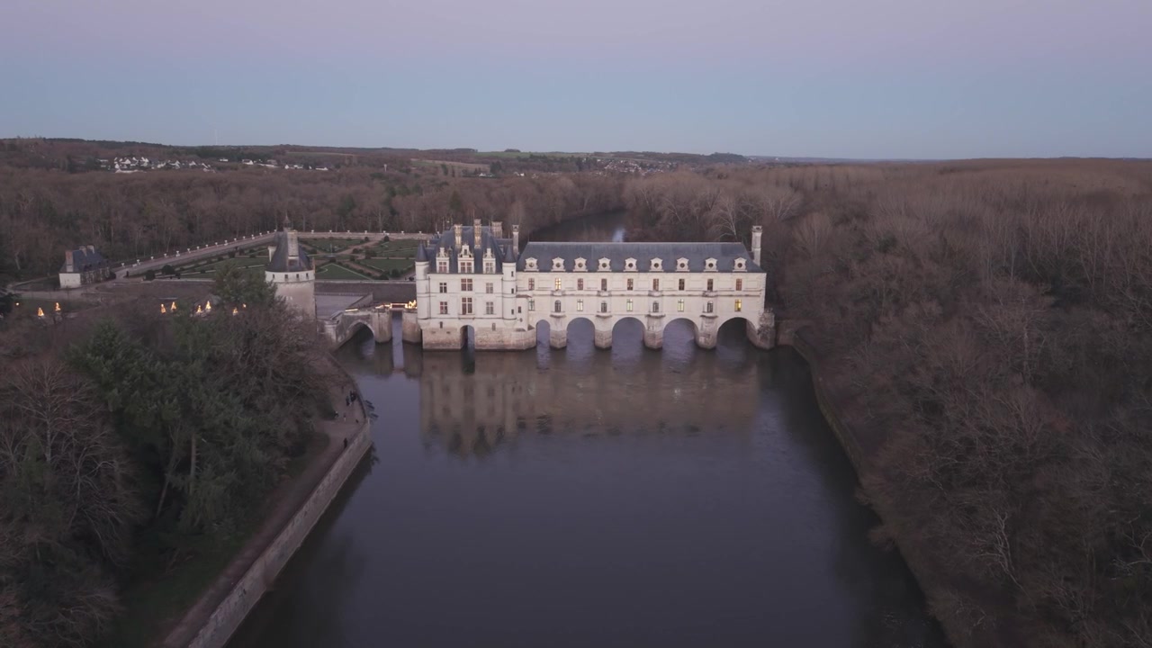 Una vista aérea del Castillo de Chenonceau, con sus galerías arqueadas que atraviesan el río y se reflejan al anochecer