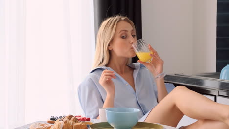 una mujer rubia desayunando en casa.