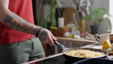 tossing spaghetti in frying pan