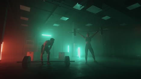 entrenamiento de levantadores de pesas profesionales hombre y mujer están levantando barra en el gimnasio oscuro gente deportiva