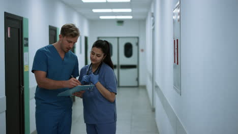 two physicians hurrying help patients after conversation in clinic corridor.