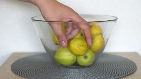 caucasian male picking up a lemon from a fruit bowl in the kitchen