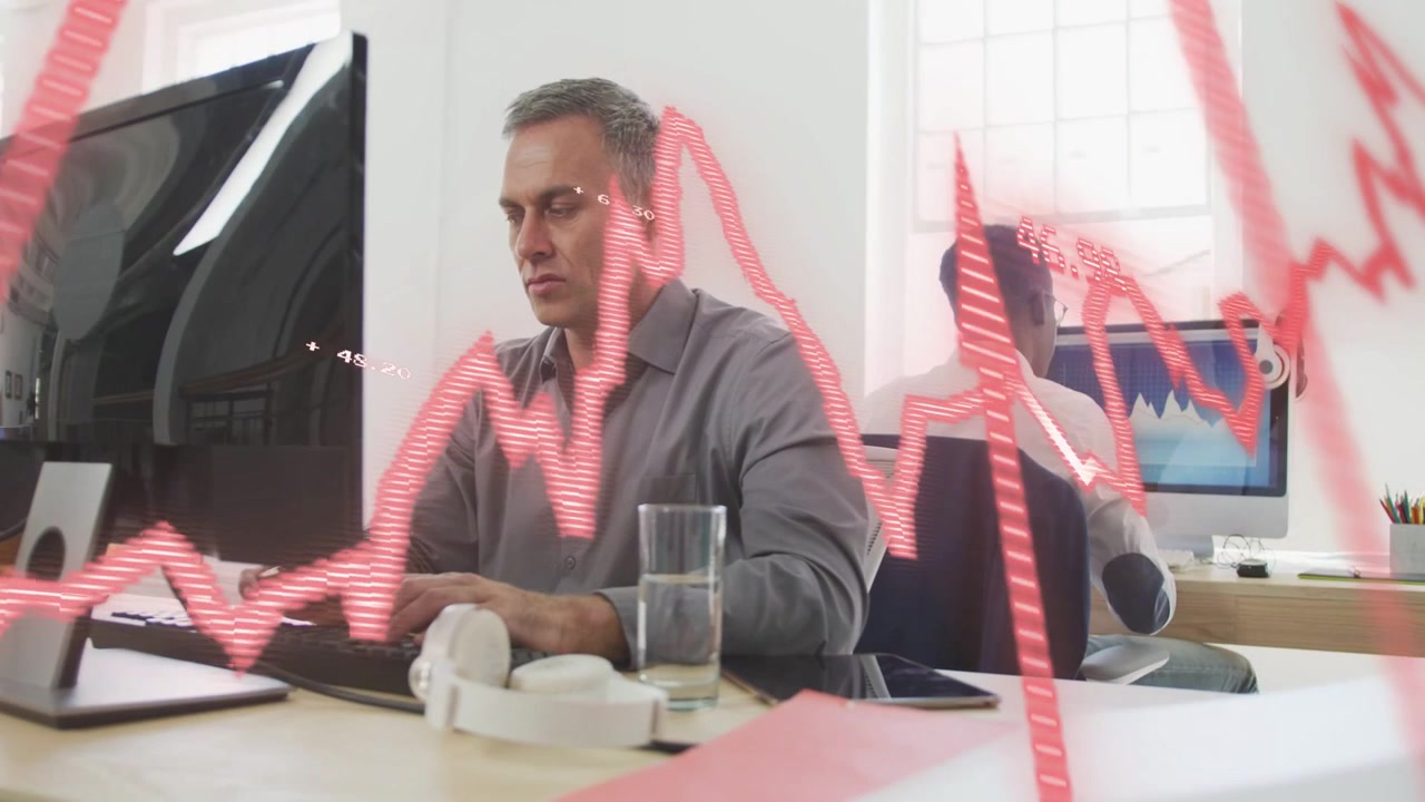 Mature man typing at desk while animated red graph sweeping screens initiating business data review