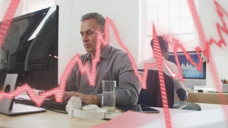 Ein reifer Mann tippt am Schreibtisch, während eine animierte rote Grafik über Bildschirme fegt und eine Geschäftsdatenprüfung einleitet.