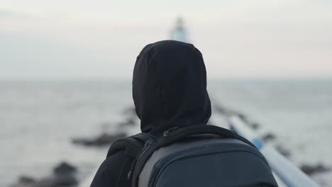 vista de la cabeza cámara lenta del hombre caminando hacia el faro.