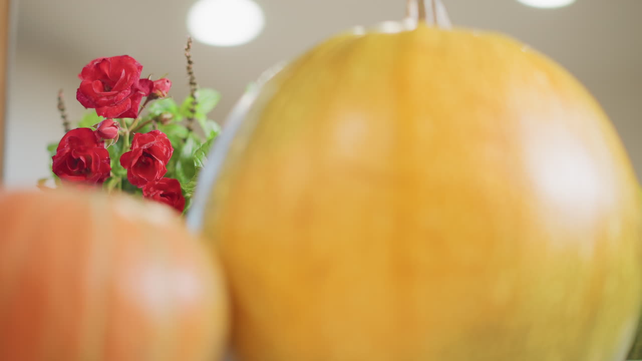 Bancone della cucina con zucche e rose, natura morta stagionale che suggerisce una cuoca casalinga che prepara ingredienti autunnali, luce calda e soffusa, profondità di campo ridotta, primo piano della texture della buccia, tonalità arancioni, accogliente.
