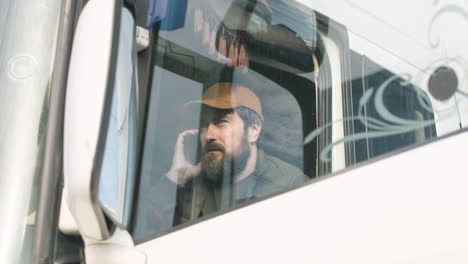 worker wearing vest and cap organizing a truck fleet in a logistics park while talking on the phone in a truck 2