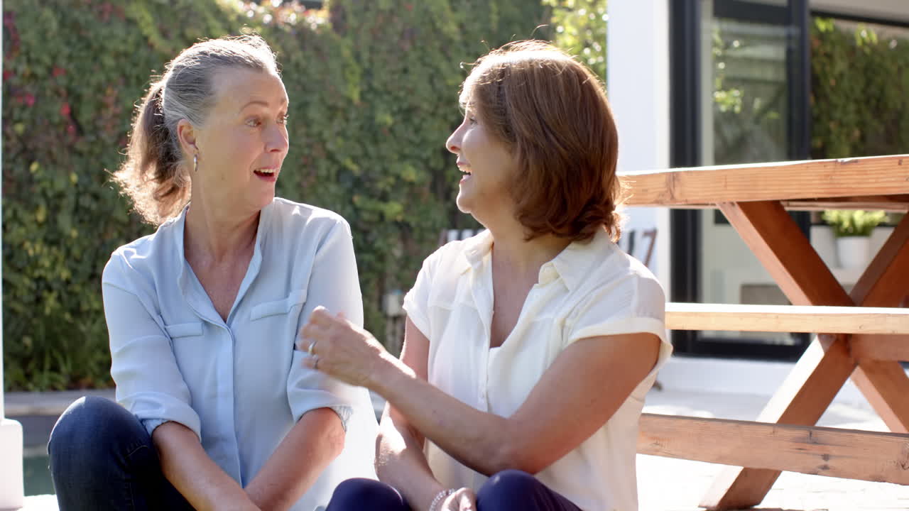 Laughing together, two senior women sitting outdoors and enjoying conversation