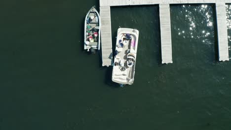 aerial top down, pontoon boat leaving docking pier on a lake during the day