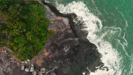 aerial view waves break on island rocks