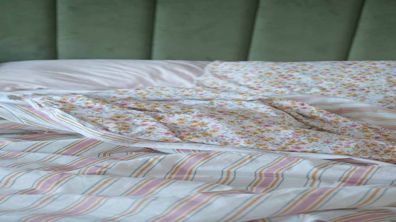 cama desordenada sin hacer con ropa de cama floral y a rayas