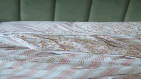 messy unmade bed with floral and striped bedding