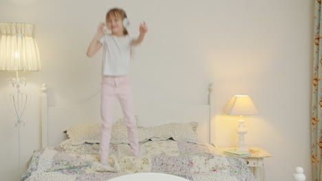 girl dancing on bed with headphones
