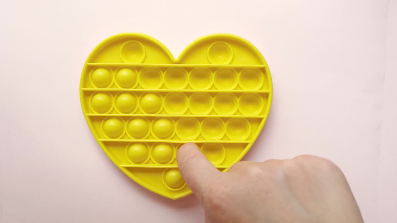 새로운 아기 장난감. 손가락 놀이. 재미있는 색. 성인 손 압축 둥근 실리콘. 형태 변경. 노란색 심장 모양
