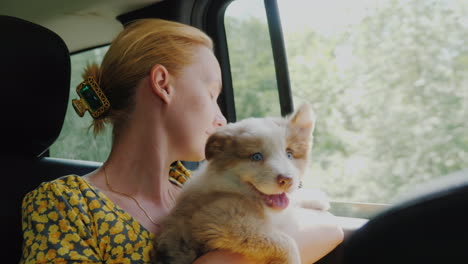 a woman with a pet travels in a car looking out the window together