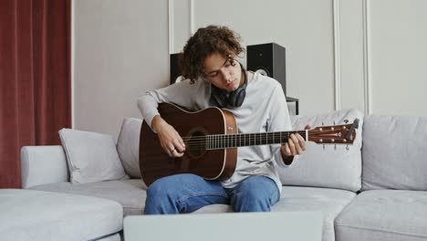 young man learning guitar at home