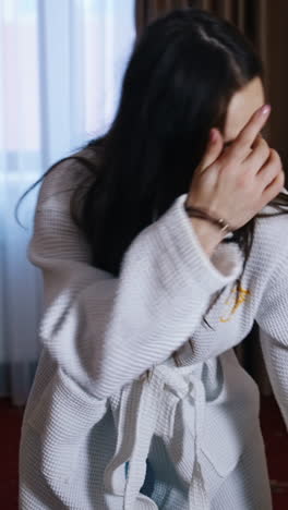 Woman unpacking luggage in hotel. Disappointed woman in white dressing gown looking at someone else's clothes in the suitcase. Vertical video