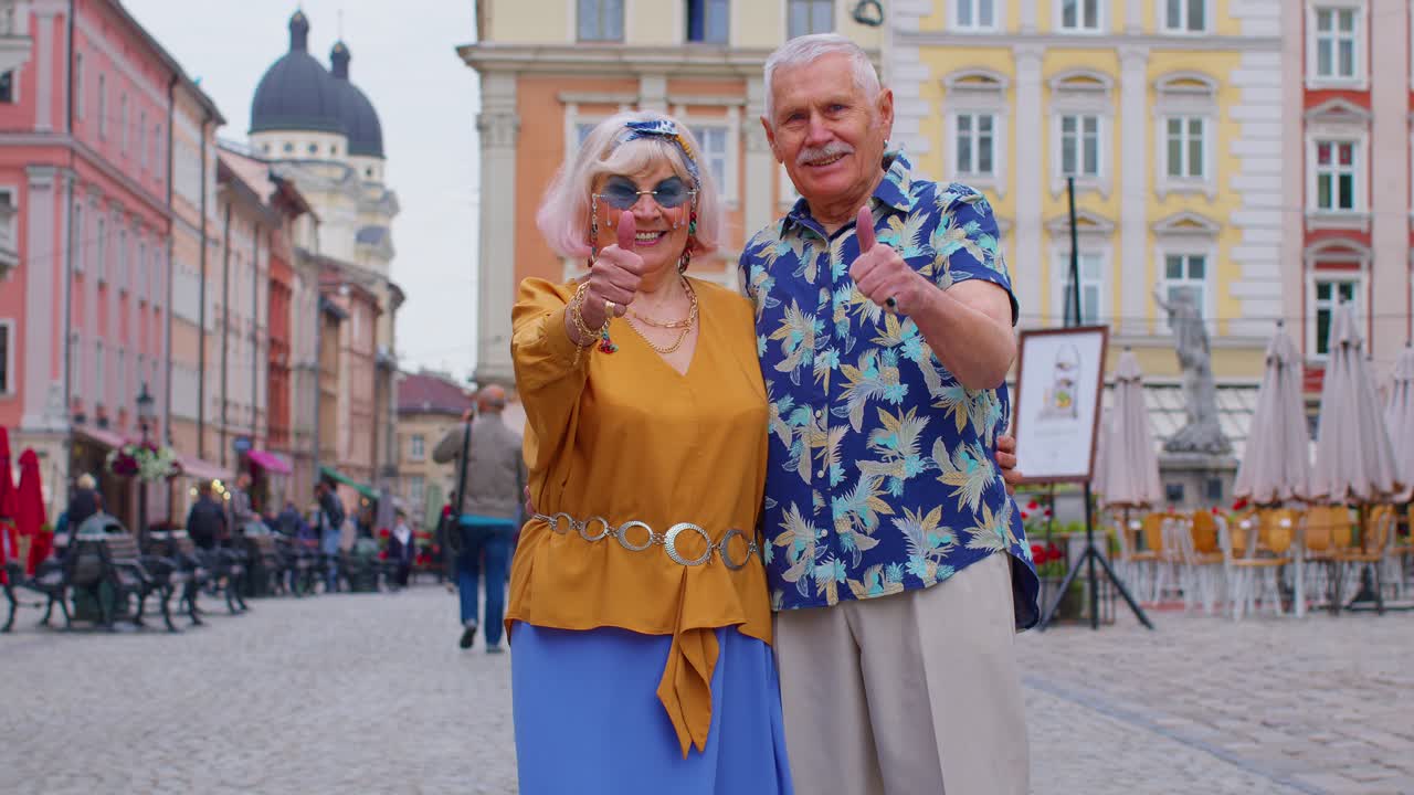 Senior grandmother grandfather tourists raises thumbs up agrees with something recommends likes good