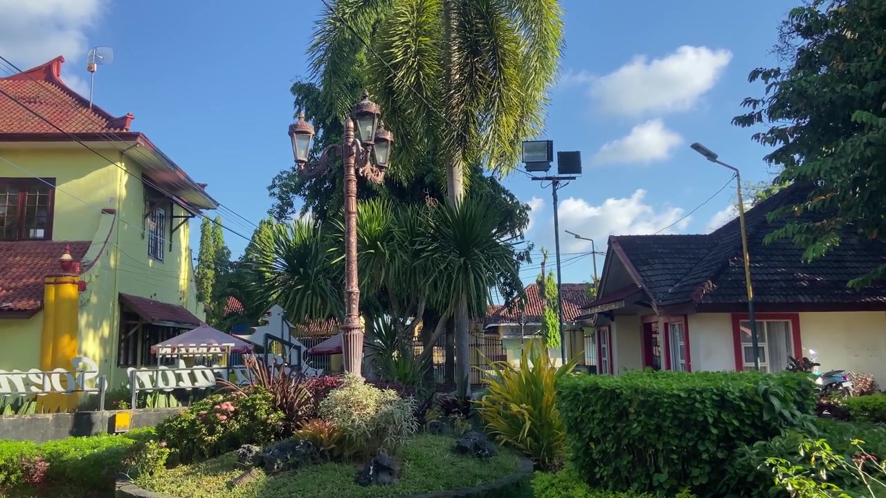 Taman Asri dengan Rumah Tradisional dan Pohon Palem