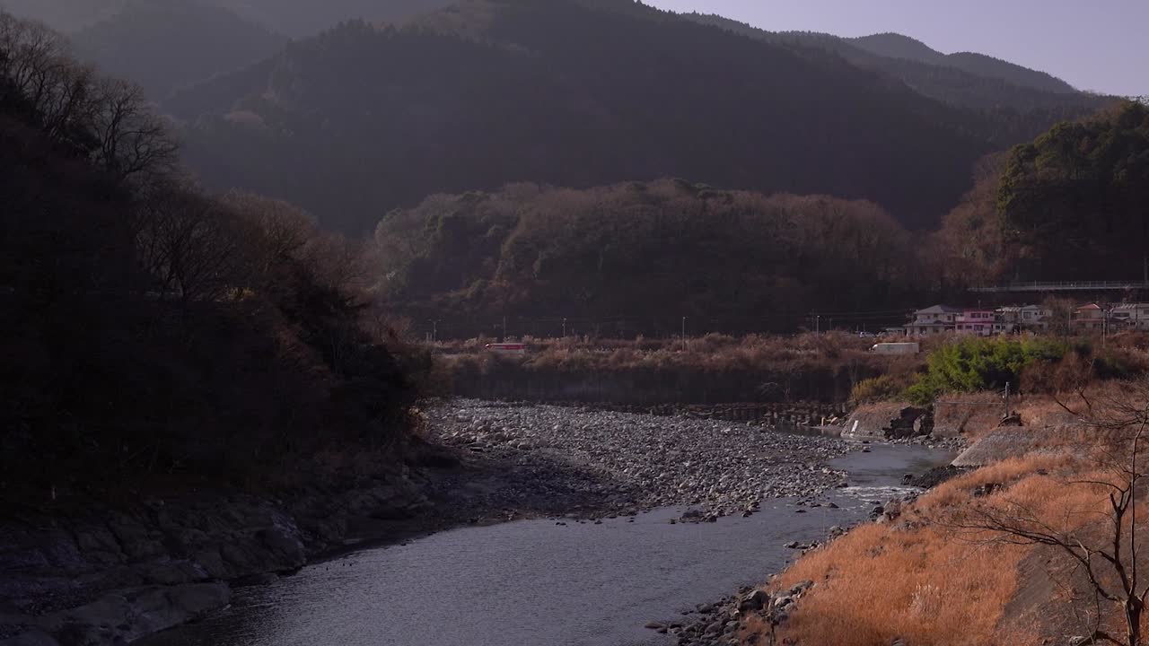 산과 자동차 교통이 있는 아름다운 시골 강 계곡 위로 천천히 기울어집니다.