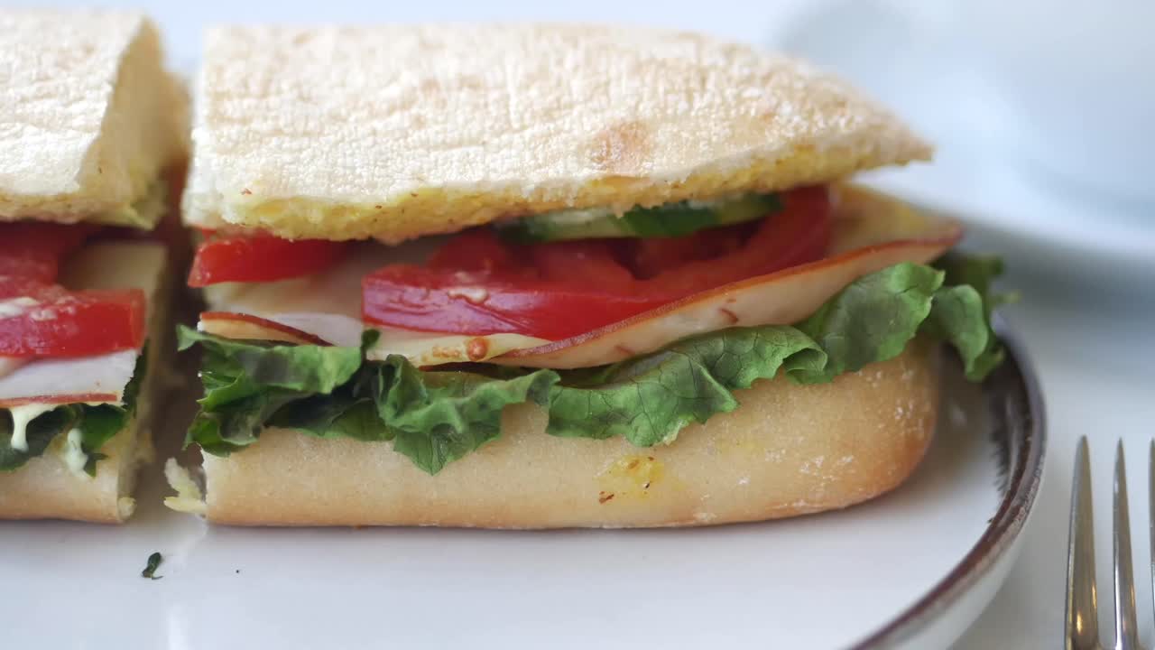 Primo piano di un panino fresco da gastronomia tagliato a metà su un piatto