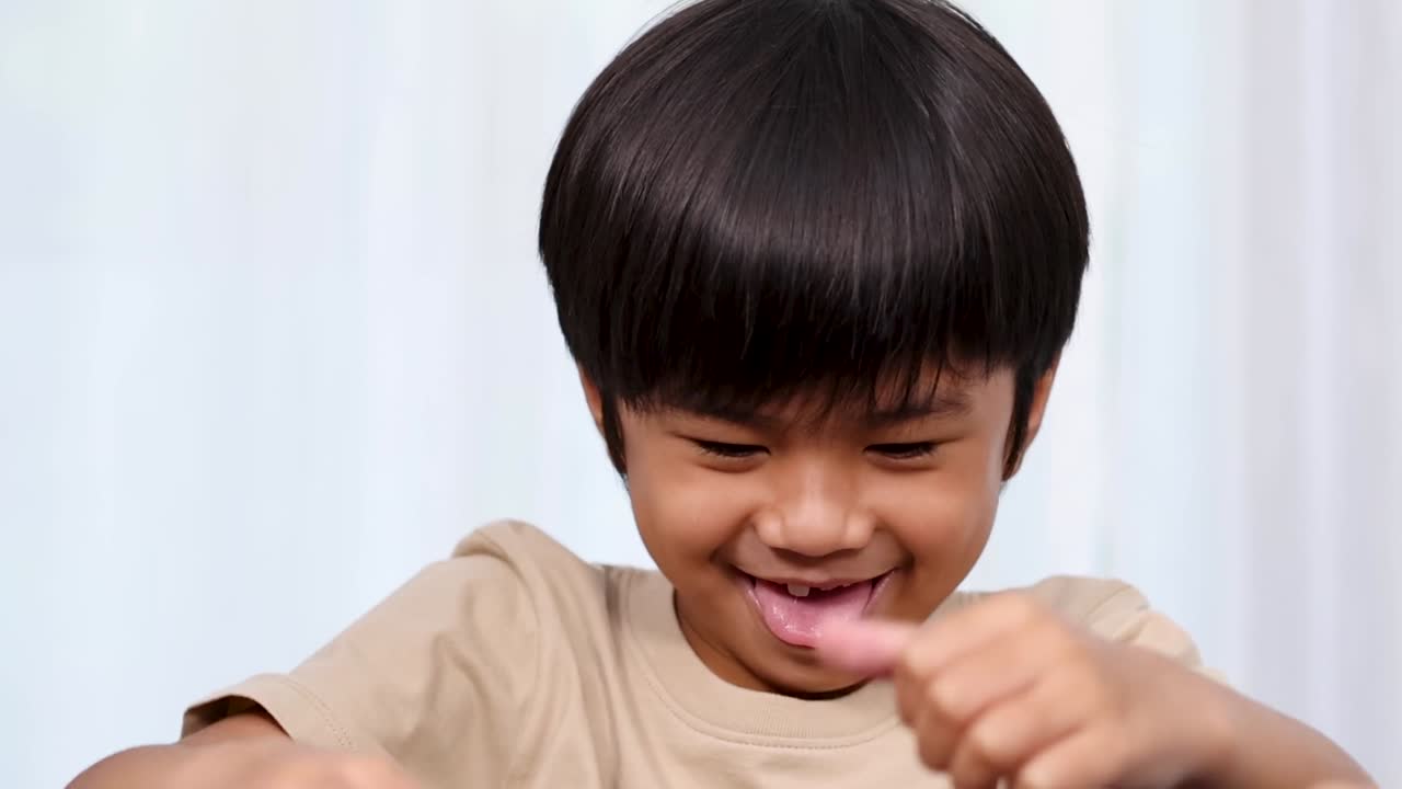 Primo piano di una bambina asiatica felice che sorride e gesticola mentre gioca con blocchi giocattolo