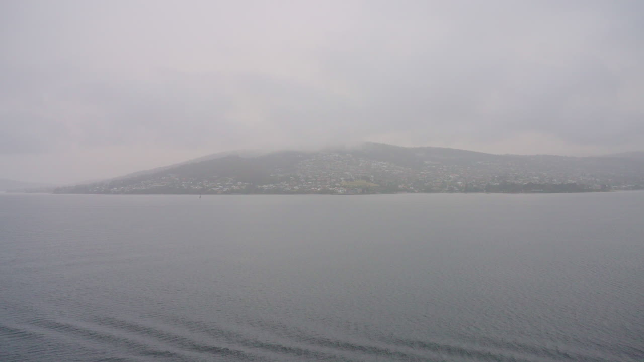 el nublado y brumoso horizonte de la montaña hobart desde la entrada del océano, 4k cámara lenta