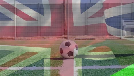 Die-Britische-Flagge-Weht-Gegen-Einen-Männlichen-Fußballspieler-Mit-Beinprothese,-Der-Den-Fußball-Kickt