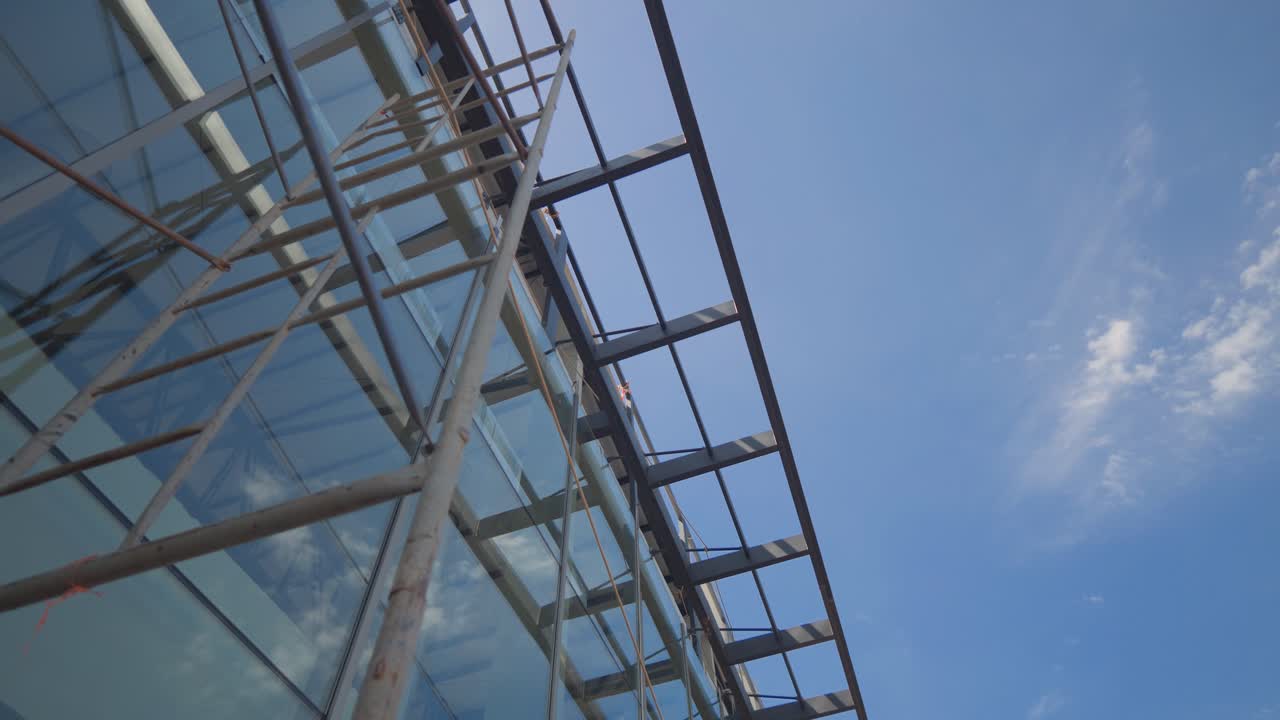 Un edificio con impalcature su un lato e un cielo blu sullo sfondo. Il cielo è limpido e luminoso, e l'edificio è alto e imponente