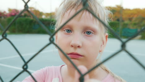 Tired-Child-Looking-Through-The-Fence-Mesh