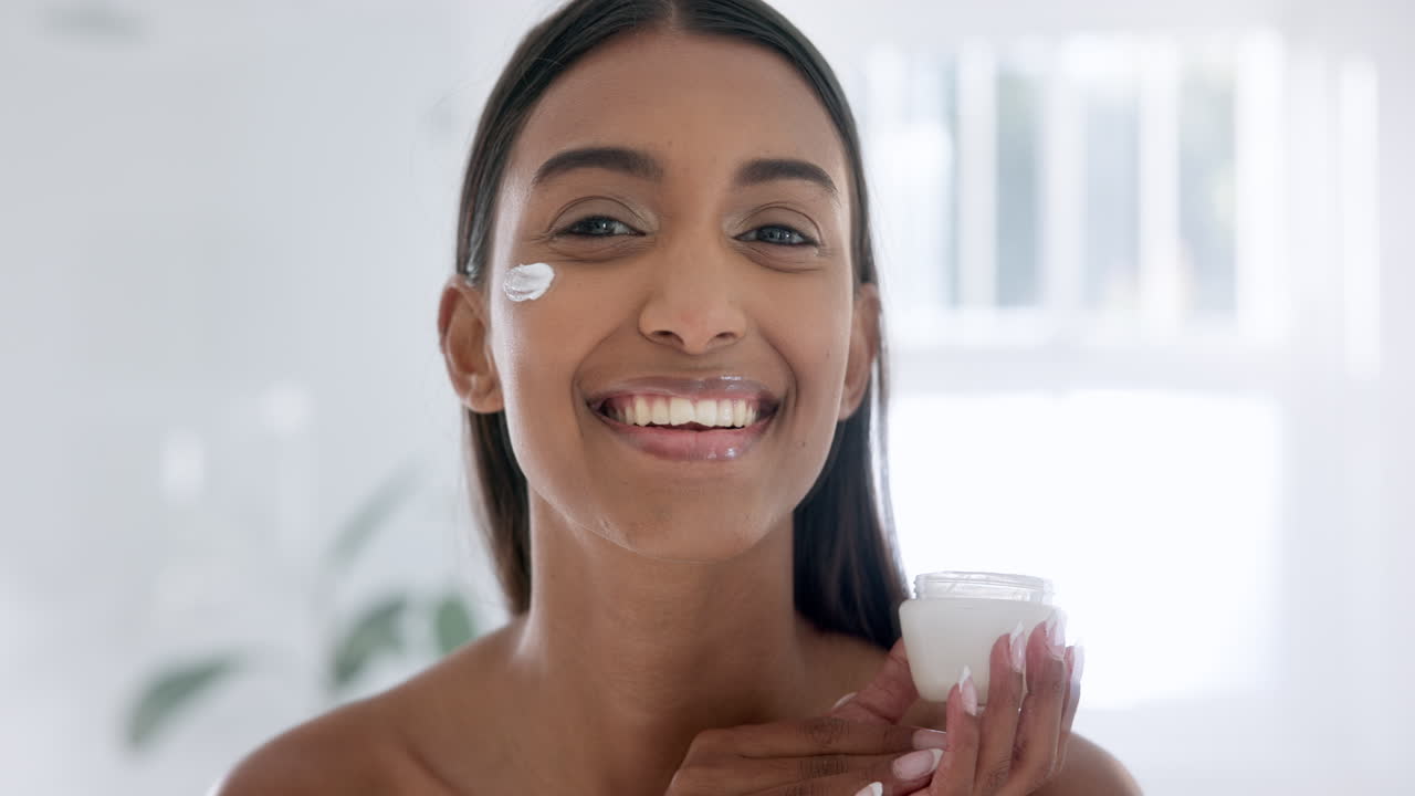 mujer, crema facial y sonrisa en el baño