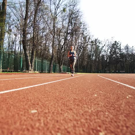 sommer training im freien. athletin beginnt auf der laufbahn zu laufen. schönes mädchen macht übungen.