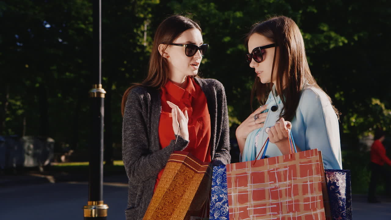 성공적인 쇼핑 경험을 한 두 명의 젊은 여성이 서로 구매한 hd 비디오를 보여줍니다.