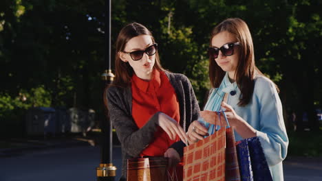 two young women after a successful shopping experience they show each other their purchases hd video