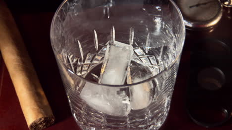 hielo caído en vaso, whisky vertido en vaso y agitado