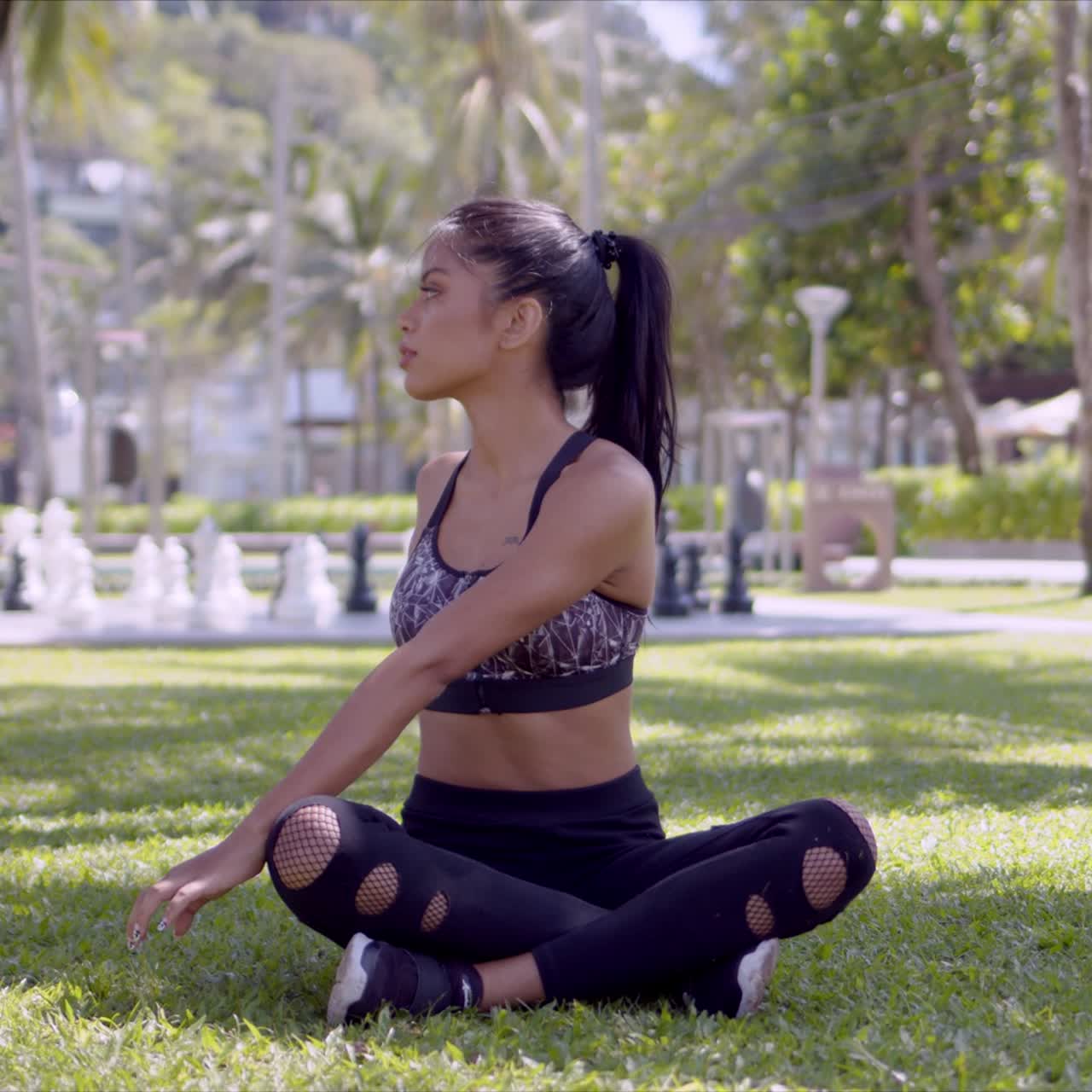 mujer relajada asiática sentada con las piernas cruzadas en el parque