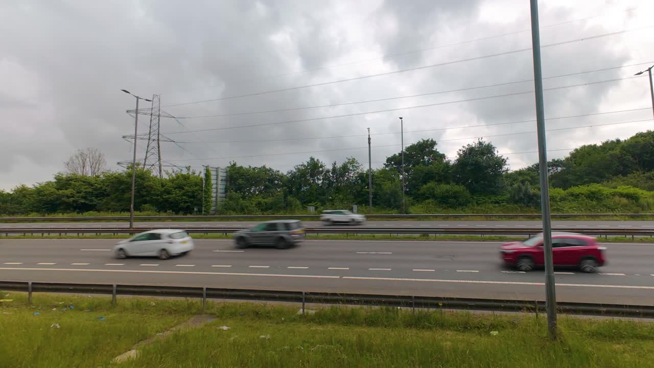 Timelapse of Motion Blurred Cars Travelling in Both Directions Along Busy Motorway with Street Lights and Electricity Pylons Overhead with Clouds Passing Quickly. M4 Dual Carriageway Road in Wales.