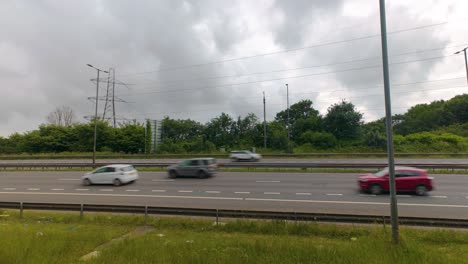 timelapse of motion blurred cars travelling in both directions along busy motorway with street lights and electricity pylons overhead with clouds passing quickly. m4 dual carriageway road in wales.