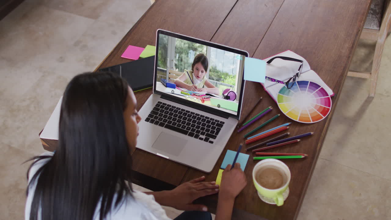 maestra caucásica usando una computadora portátil en videollamada con una colegiala, tomando notas