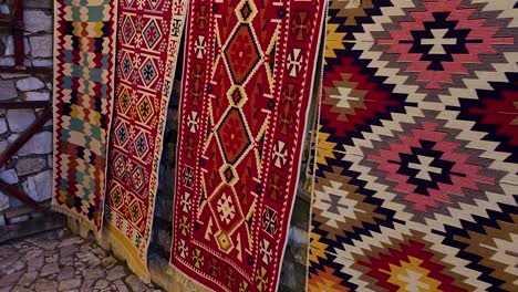 las alfombras adornan las paredes de piedra del castillo de berat, tapicería artesanal hecha a mano de colores y formas en albania