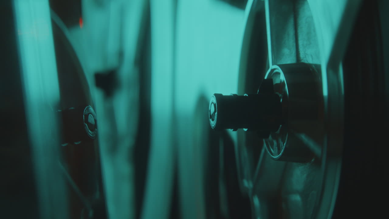 Close-Up of Tape Reels Spinning as Playing Music in Dark Studio with Neon Light